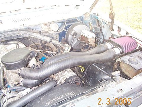 1986 Ford Bronco - Close-up view of a vehicle's engine bay, an aftermarket air intake system and various hoses.