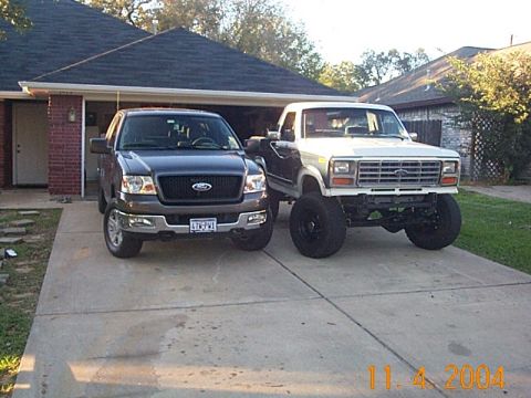 1986 Ford Bronco - A lifted 1980s Ford truck is parked next to a more modern Ford F-150 in a suburban driveway.