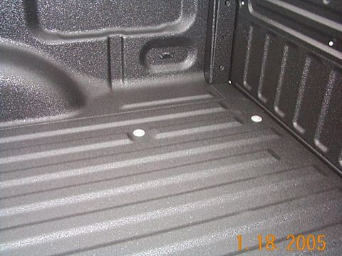 1986 Ford Bronco - Close-up view of a textured truck bed liner, showing the ribbed floor and tie-down anchor points.