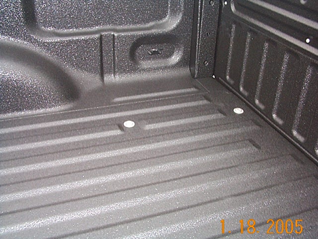 Truck bed corner with textured black spray-in bedliner, dated Jan 2005