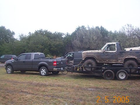 1986 Ford Bronco - A muddy Ford Bronco is transported on a trailer behind a Ford F-150 pickup truck.