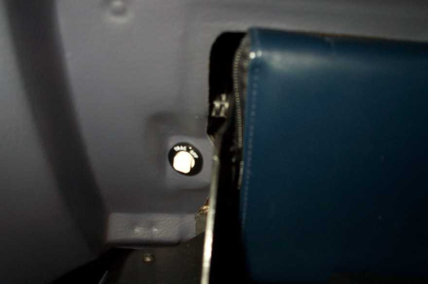 Close-up of body panel seam near a blue seat with a metal fastener or grommet