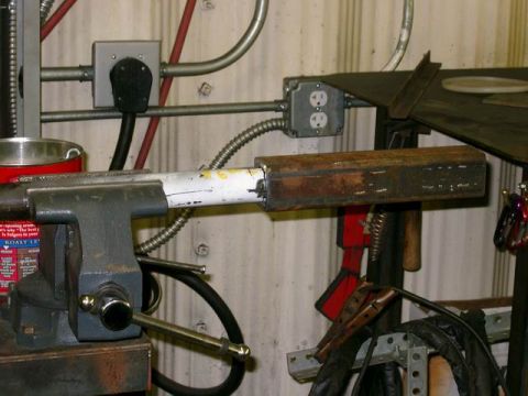 1996 Ford Bronco - A metal pipe is secured in a vise, with various workshop tools and electrical components visible.