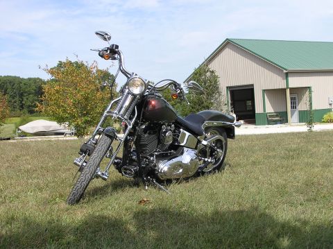 1995 Mercury Grand Marquis - A motorcycle sits on a grassy lawn before a barn, under a partly cloudy sky.