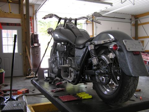 1995 Mercury Grand Marquis - A motorcycle is elevated on a lift inside a garage, with tools scattered nearby.
