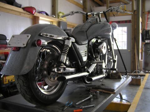 1995 Mercury Grand Marquis - A custom motorcycle is shown from the rear, resting on a workbench in a garage setting.