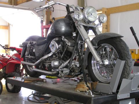 1995 Mercury Grand Marquis - Motorcycle on a lift with a red ATV visible behind it in a garage.