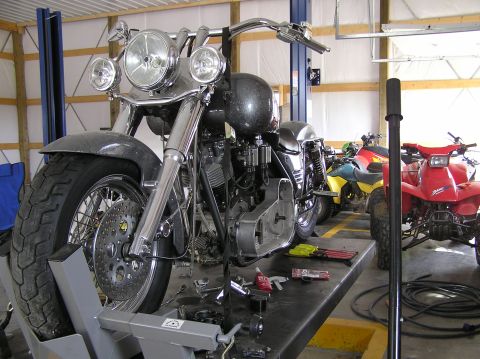 1995 Mercury Grand Marquis - A motorcycle is being worked on in a garage, with other vehicles visible in the background.