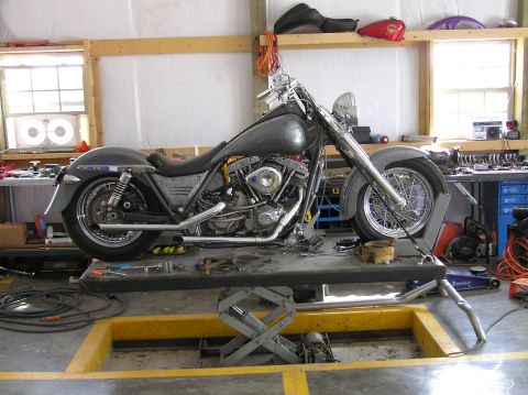 1995 Mercury Grand Marquis - Motorcycle is on a lift in a workshop environment with various tools and parts around.