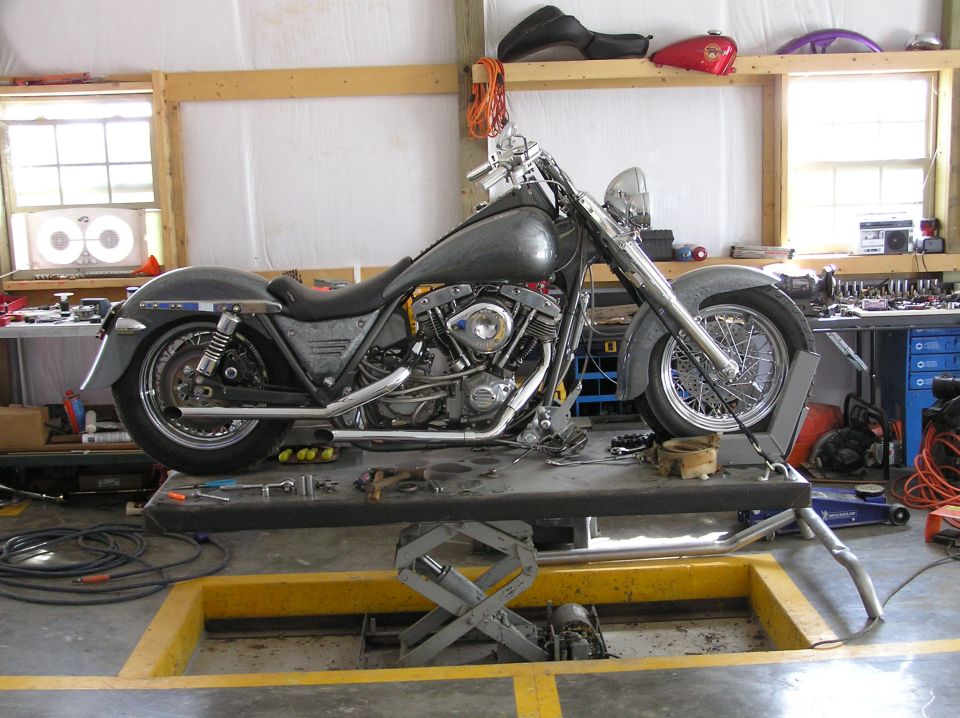Motorcycle on a lift in a garage with tools and parts visible