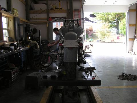 1995 Mercury Grand Marquis - A motorcycle is being worked on inside a garage with the bay door open.