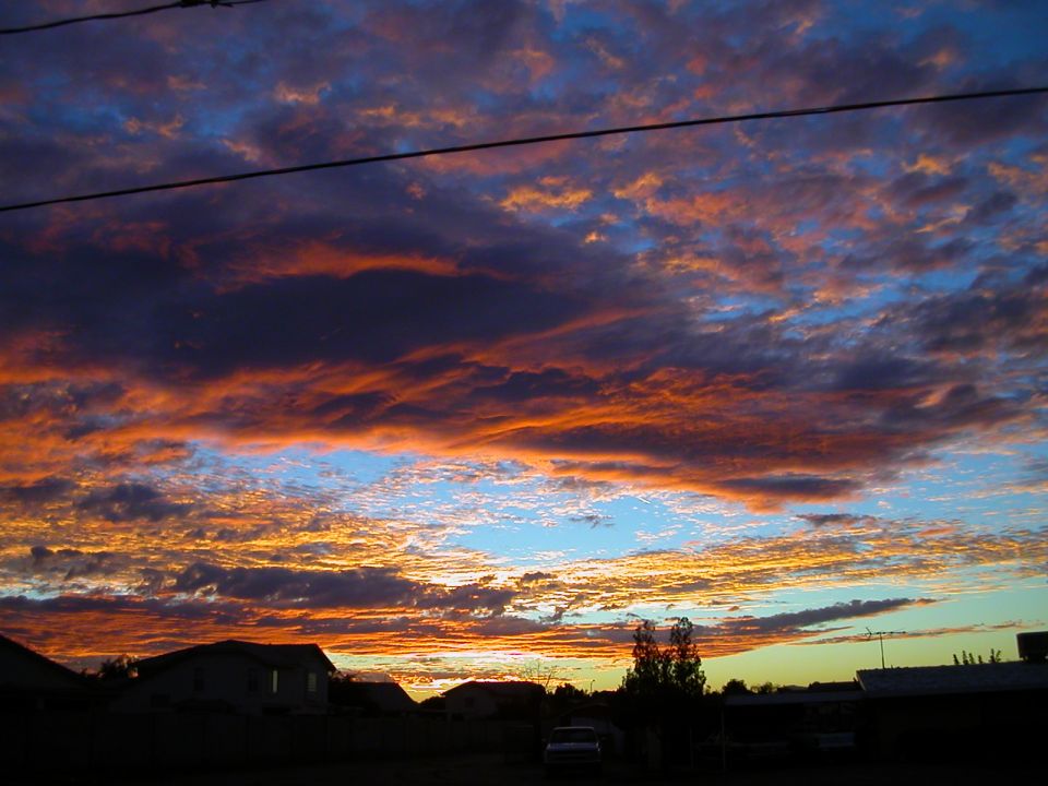 Sunset clouds over houses with a faint vehicle in the distance
