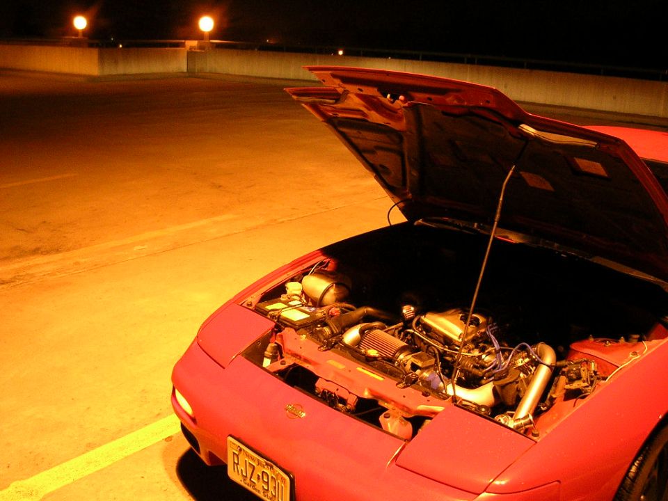 Red sports car with hood open showing engine bay. License plate RJZ-930