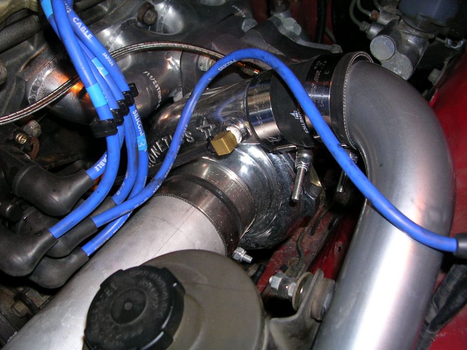 Polished intercooler piping with silicone couplers and blue plug wires in an engine bay