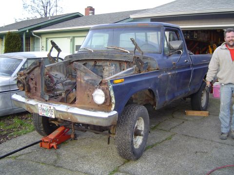 1979 Ford Bronco - This blue pickup truck has its front end removed for repairs or parts. A second vehicle is visible to the left.