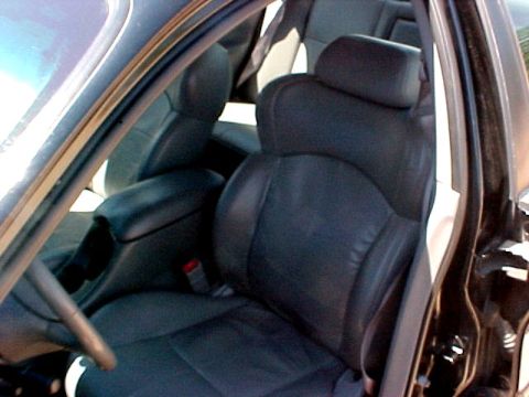1997 Ford Expedition - The interior of a vehicle shows black leather seats and a center console with a seatbelt visible.