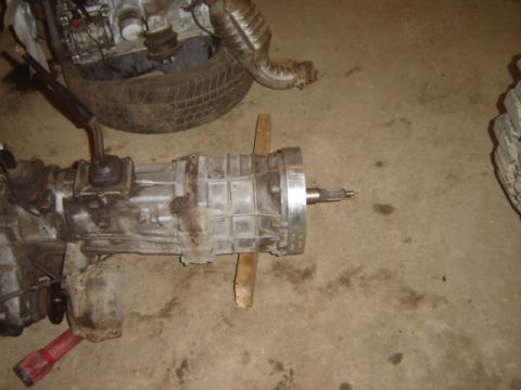 1992 Ford Bronco - Transmission and engine components are laid out on a concrete surface, with a red tool in the foreground.