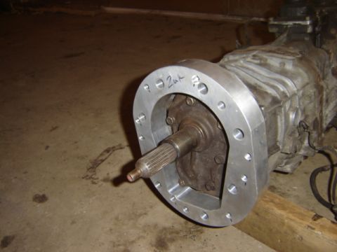 1992 Ford Bronco - A close-up view of a transmission adapter plate, with handwritten markings, attached to a transmission assembly.