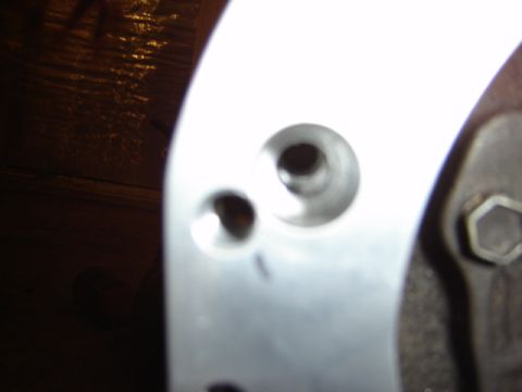1992 Ford Bronco - Metal part with holes and a bolt, likely from a vehicle's engine or chassis.
