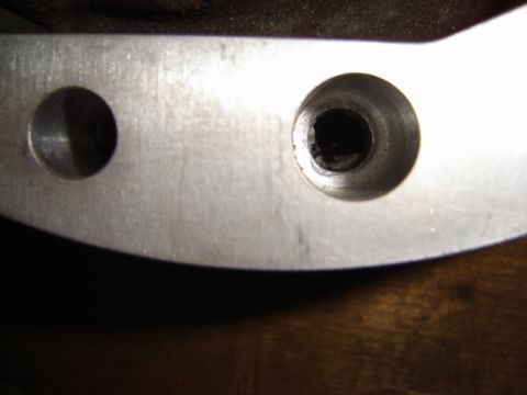 1992 Ford Bronco - Close-up of a metal bracket with two holes, one showing signs of damage.