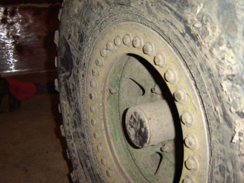 1992 Ford Bronco - Close-up of a heavily used wheel and tire assembly, showing a beadlock ring and a green hub.