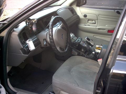 2001 Ford Crown Victoria - The interior of a 2001 Ford Crown Victoria police car is visible, equipped with numerous communication devices.