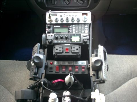 2001 Ford Crown Victoria - Custom electronic console with multiple radios and switches installed in a vehicle's interior.