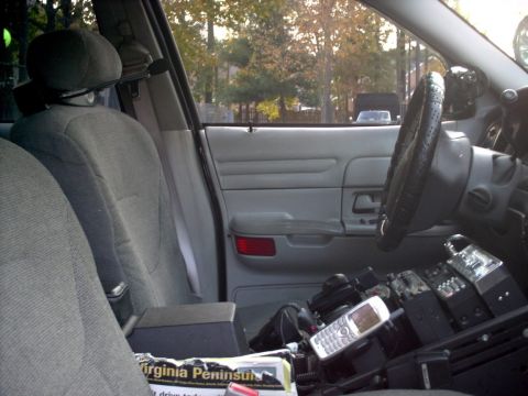 2001 Ford Crown Victoria - The interior of a 2001 Ford Crown Victoria police car shows radio equipment, a cell phone, and a view of the exterior through the windows.