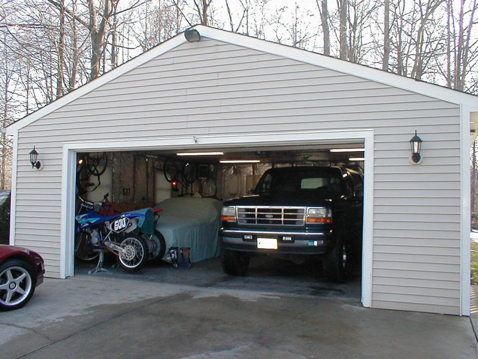 Black Ford Bronco SUV parked in a garage bay next to dirt bikes