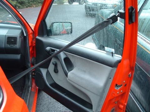 1994 Volkswagen Jetta - Interior view of an orange car door, showing the door panel and seatbelt, with other vehicles visible through the window.