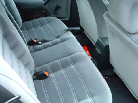 1994 Volkswagen Jetta - Rear interior view of a car showing gray cloth seats and seatbelts, with a fire extinguisher on the floor.