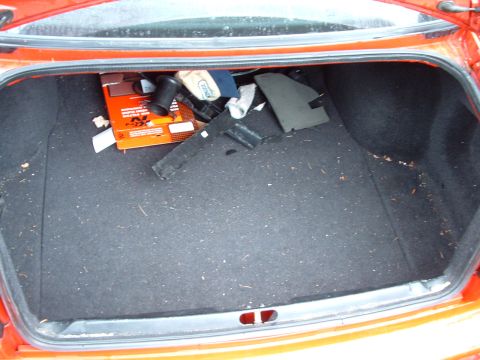 1994 Volkswagen Jetta - The open trunk of an orange vehicle contains various items, including an air filter box and plastic components.