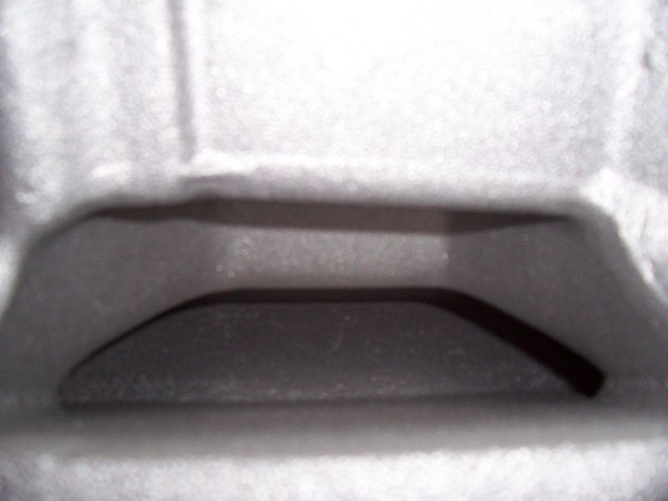 Close-up of a dark, curved metal part inside a textured, light-colored casing