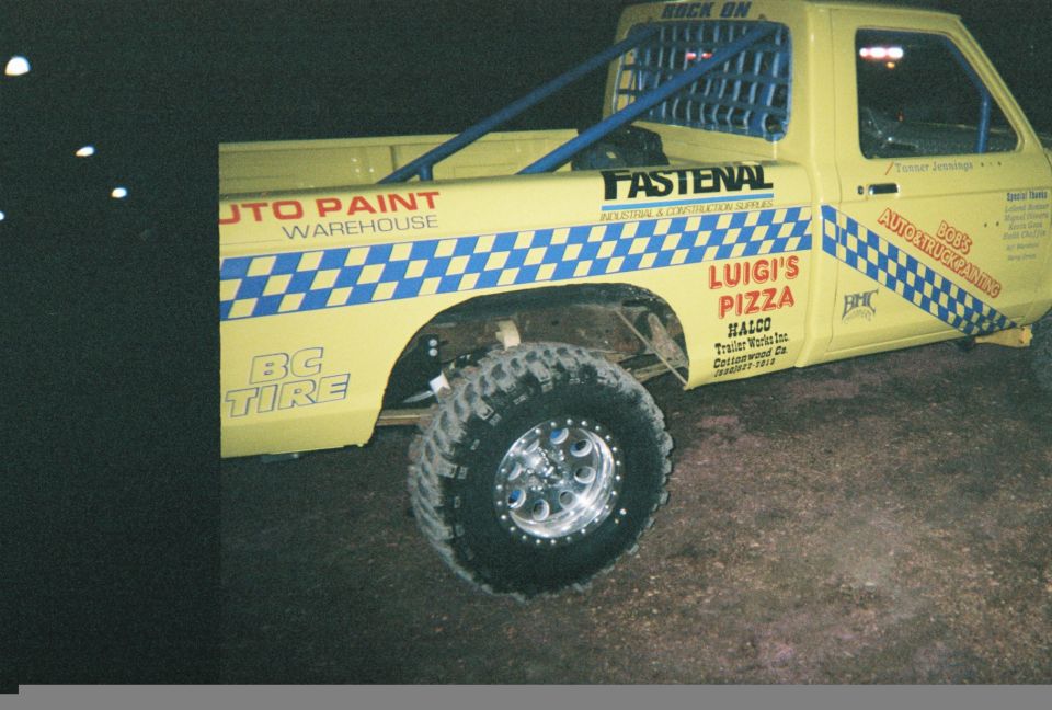 Yellow pickup truck side view with 'Luigi's Pizza' and 'Auto Paint Warehouse' decals