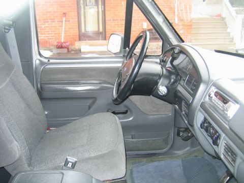 1992 Ford Bronco - The interior of a 1992 Ford Bronco features a gray fabric seat and a dashboard with a radio and climate controls.
