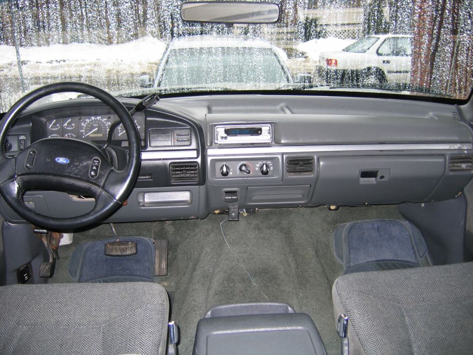 1992 Ford Bronco interior showing dashboard, steering wheel, and seats. Two other vehicles visible through the windshield