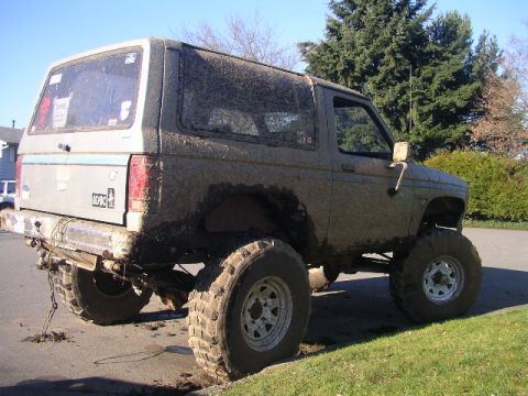 1984 Ford Bronco II - This lifted 1984 Ford Bronco II is covered in mud, suggesting recent off-road use.