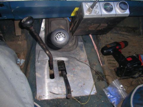 1984 Ford Bronco II - The interior of a vehicle shows two gear shifters, a CB radio, and a cordless drill on the floor.