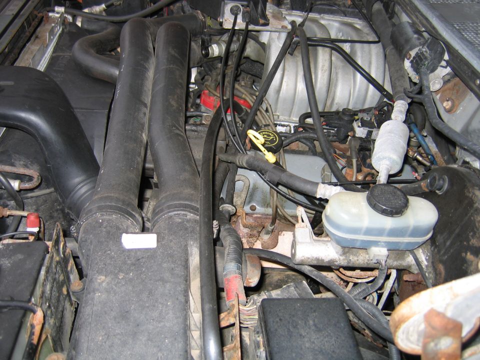 1992 Ford Bronco engine bay with dual intake tubes, brake fluid reservoir, and various hoses and wires