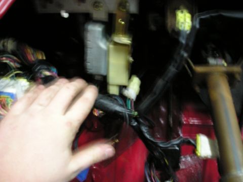 1994 Ford Probe - A hand is shown interacting with a tangled mass of wires and electrical connectors inside a vehicle's interior.
