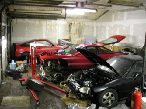 1994 Ford Probe - A garage scene with multiple vehicles in various states of disassembly, suggesting ongoing project work.