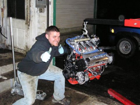 1994 Ford Probe - A man gives a thumbs up as a car engine is hoisted out of a garage.