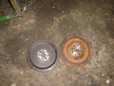 1992 Ford Bronco - Two flywheels are shown on a concrete floor, one appearing to be in better condition than the other.