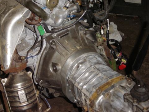 1992 Ford Bronco - Close-up view of engine and transmission parts, including a catalytic converter, with visible wiring and hoses.