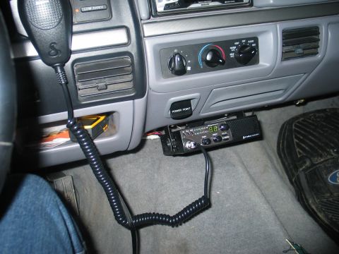 1995 Ford Bronco - Interior view of a Ford truck's lower dashboard showing a Cobra CB radio mounted under the center dash near the transmission tunnel, with a…