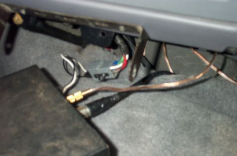 1995 Ford Bronco - A close-up under the dashboard of a vehicle showing wiring, including a multi-colored (red, green, blue) ribbon connector, black and copper…