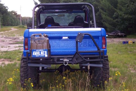 1974 Ford Bronco - A blue 1974 Ford Bronco is viewed from the rear, equipped with off-road accessories like accessories.