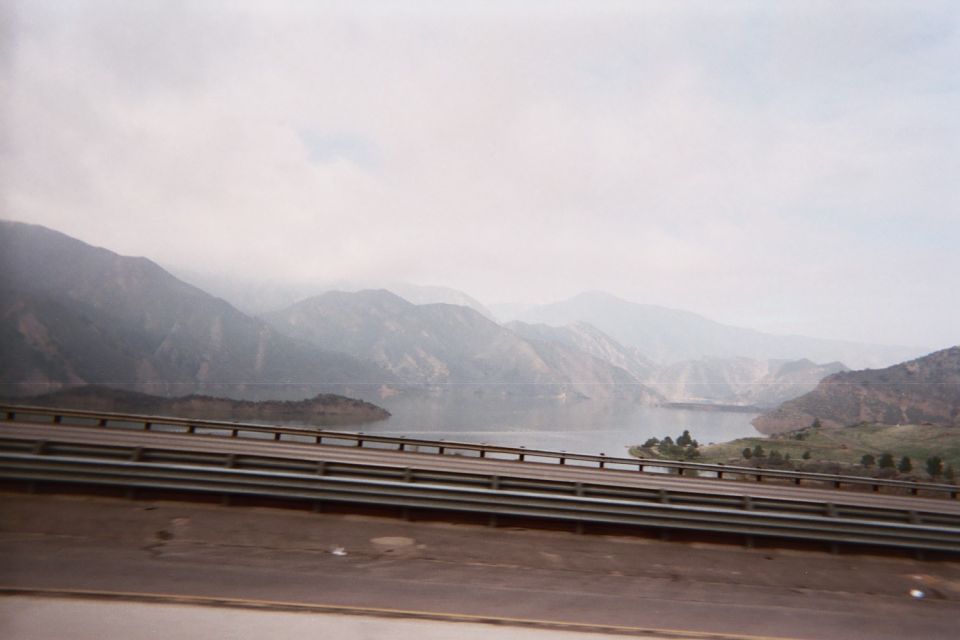 Hazy reservoir and mountains seen over a metal guardrail