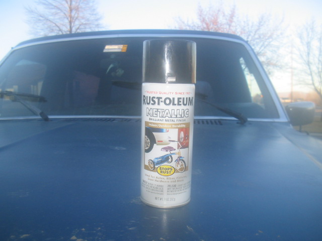 Rust-Oleum Metallic spray paint can standing on the blue hood of a square-body truck