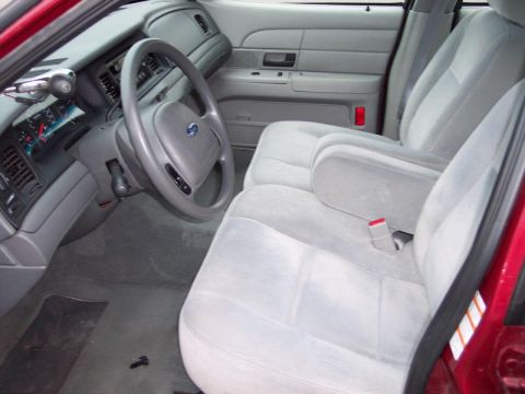 1999 Ford Crown Victoria - Interior view of a red car, showing gray cloth seats and the dashboard area.
